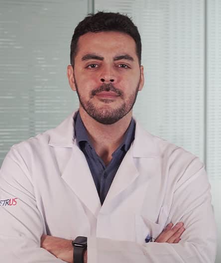 Dr. Delmar Junior, coordenador do curso de Pós-Graduação Lato Sensu em Cardiointensivismo do Cetrus, vestindo jaleco branco com o logotipo do Cetrus na manga, posando com os braços cruzados.