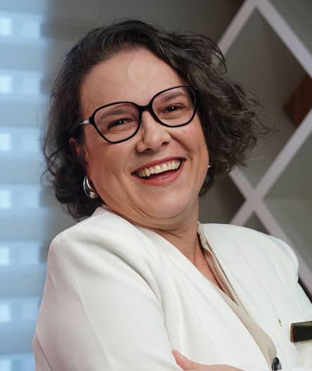 Dra. Cynthia Lins, coordenadora do fellowship em Ultrassonografia Ginecológica e Obstétrica do Cetrus, sorrindo, vestida com blazer branco e óculos.